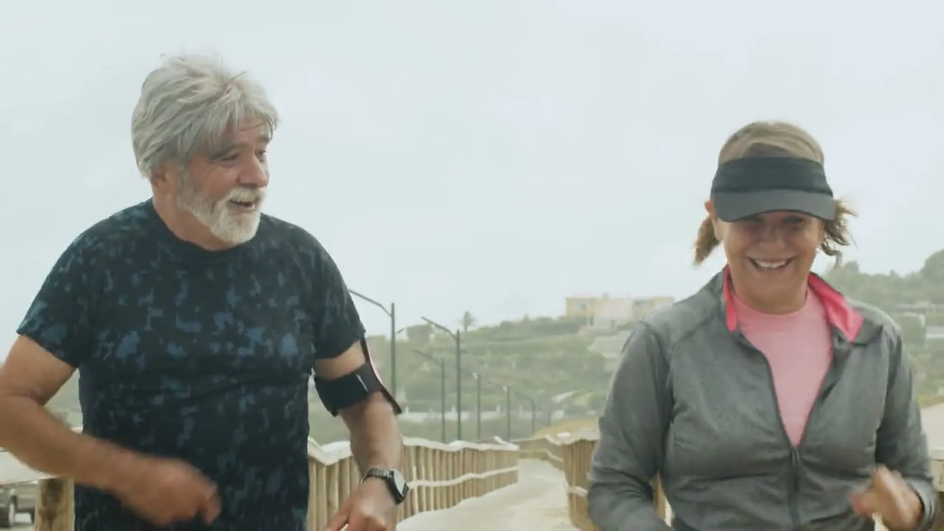 Una pareja de unos sesenta años trota sonriente junto al mar