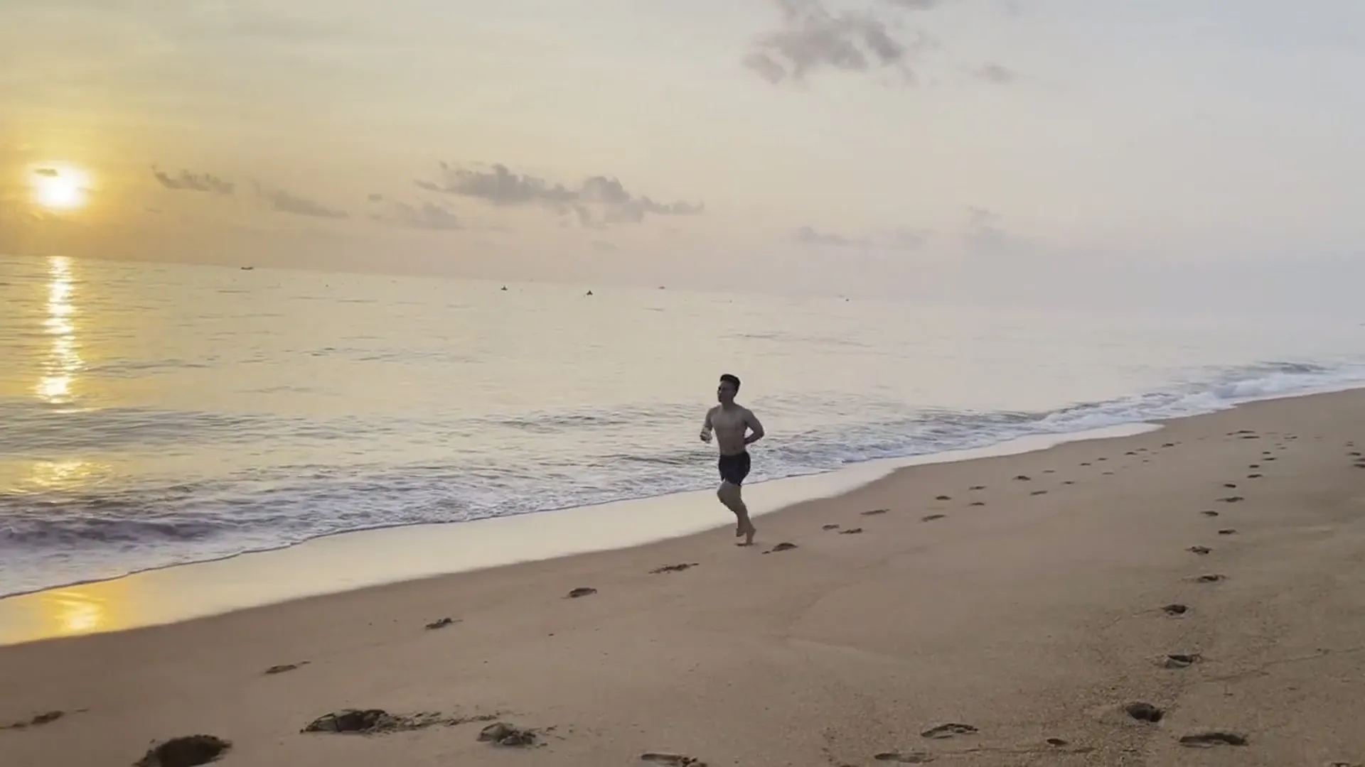 Una persona corre por la playa al amanecer